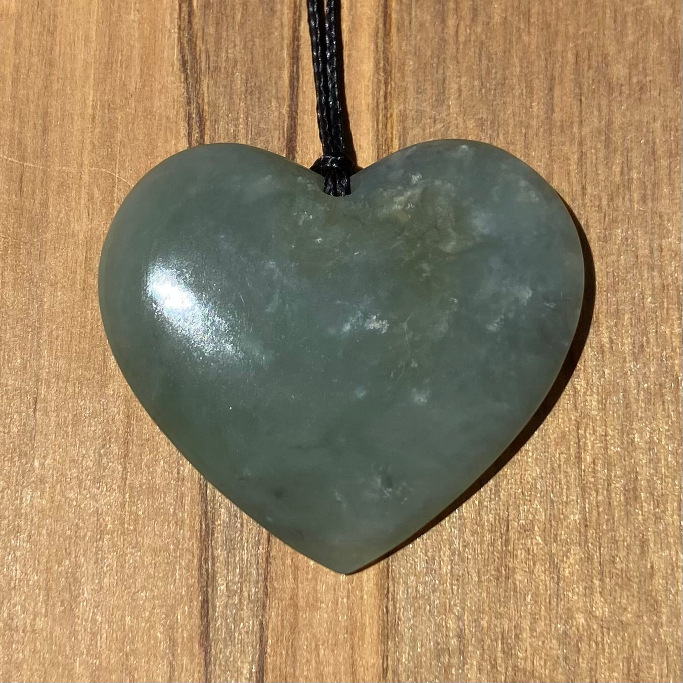Heart shaped pendant hand-carved from New Zealand inanga pounamu (greenstone). Front.