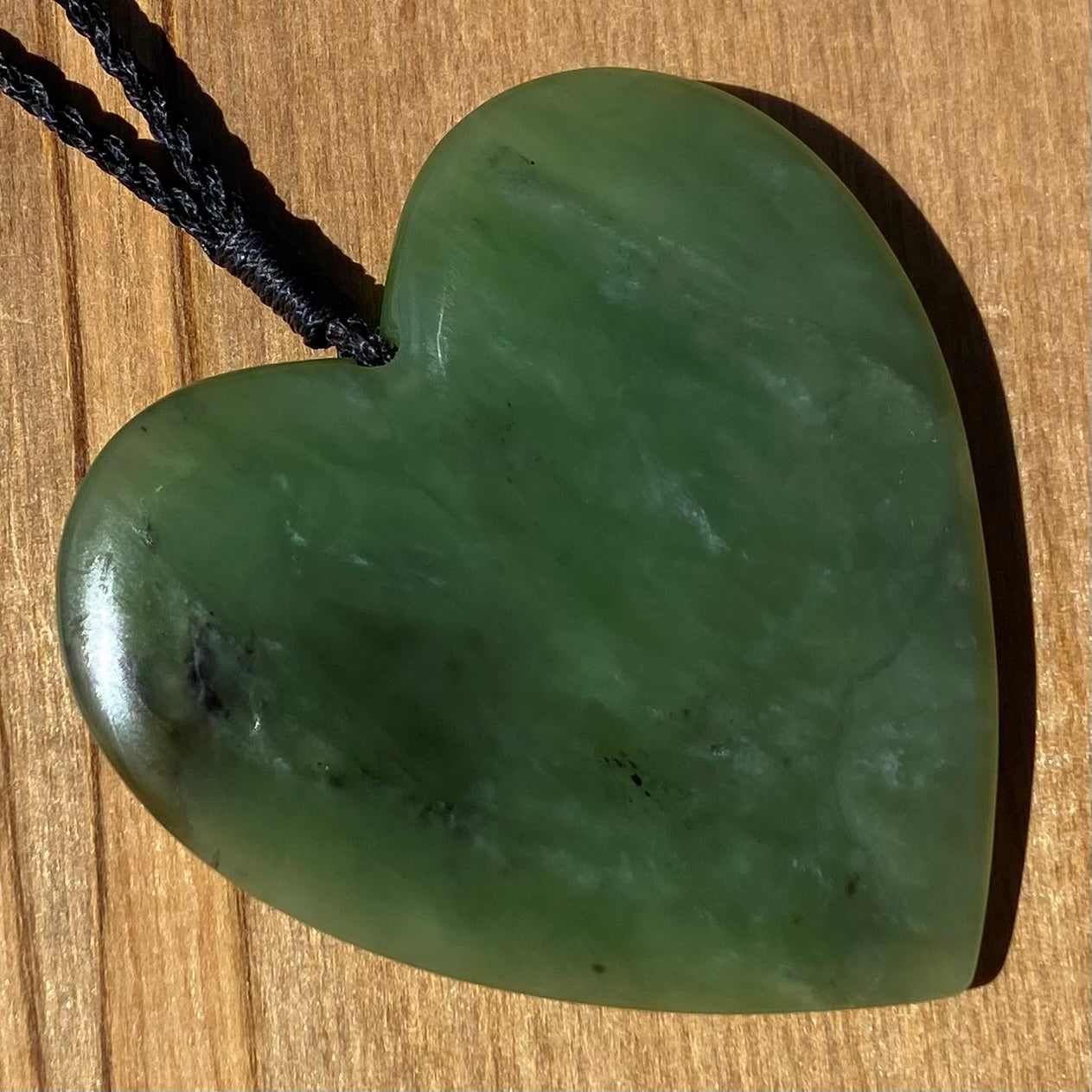 Heart pendant hand-carved from New Zealand kawawkawa pounamu (greenstone). Angle.