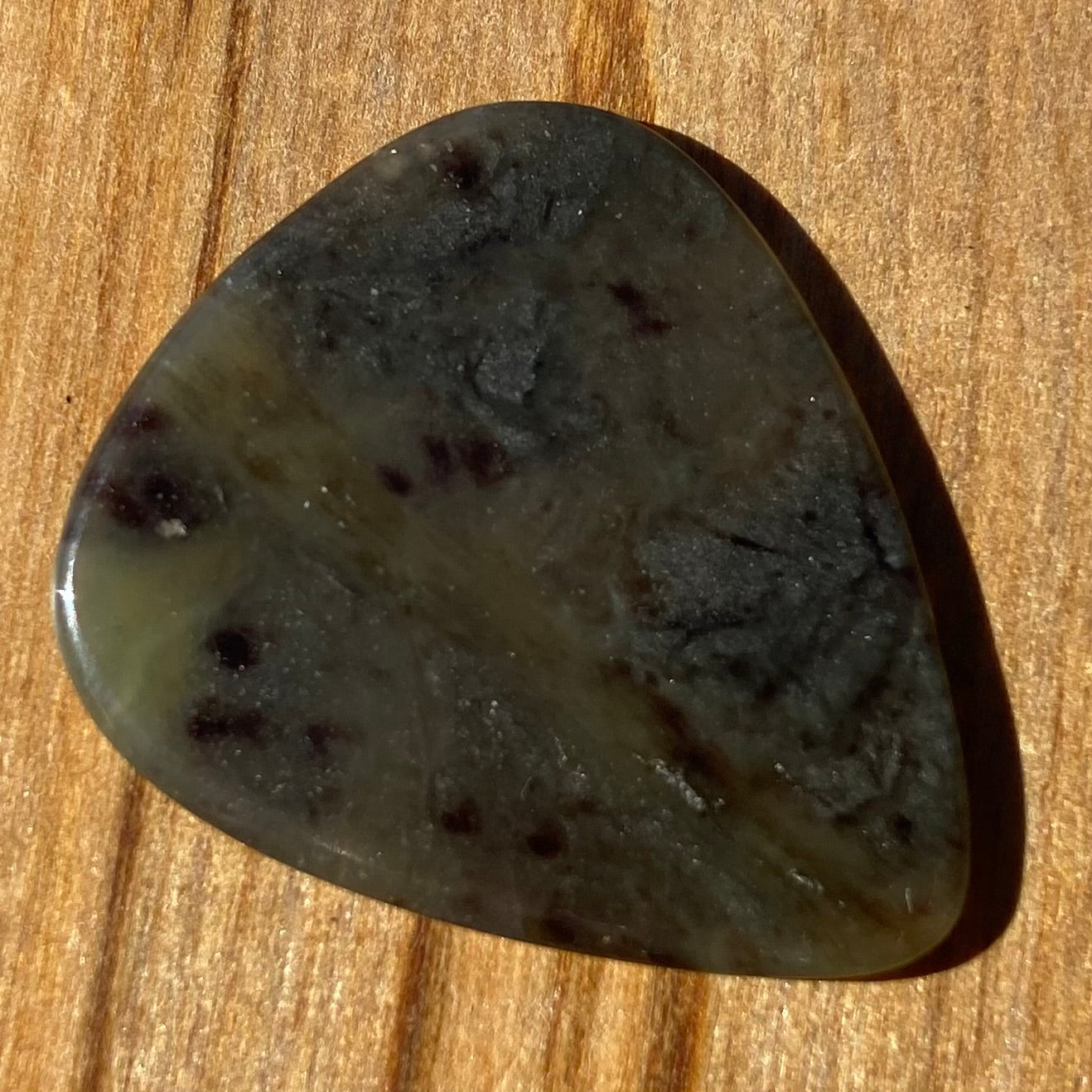 Guitar pick hand-carved from New Zealand Kawakawa Greenstone pounamu (greenstone). Front.