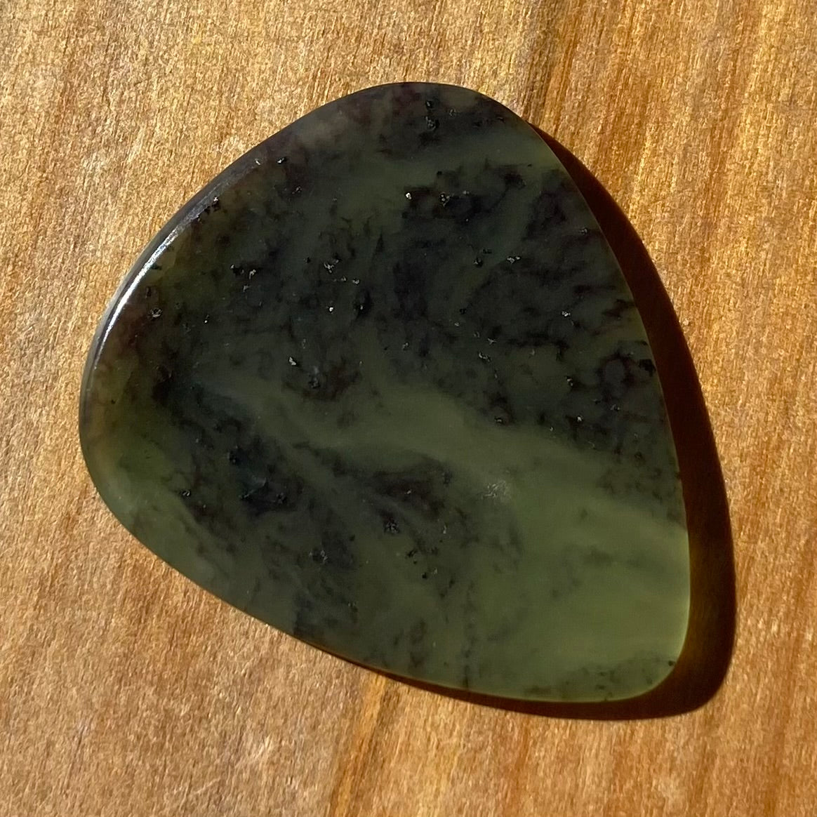 Guitar pick hand-carved from New Zealand Kawakawa Greenstone pounamu (greenstone). Front.