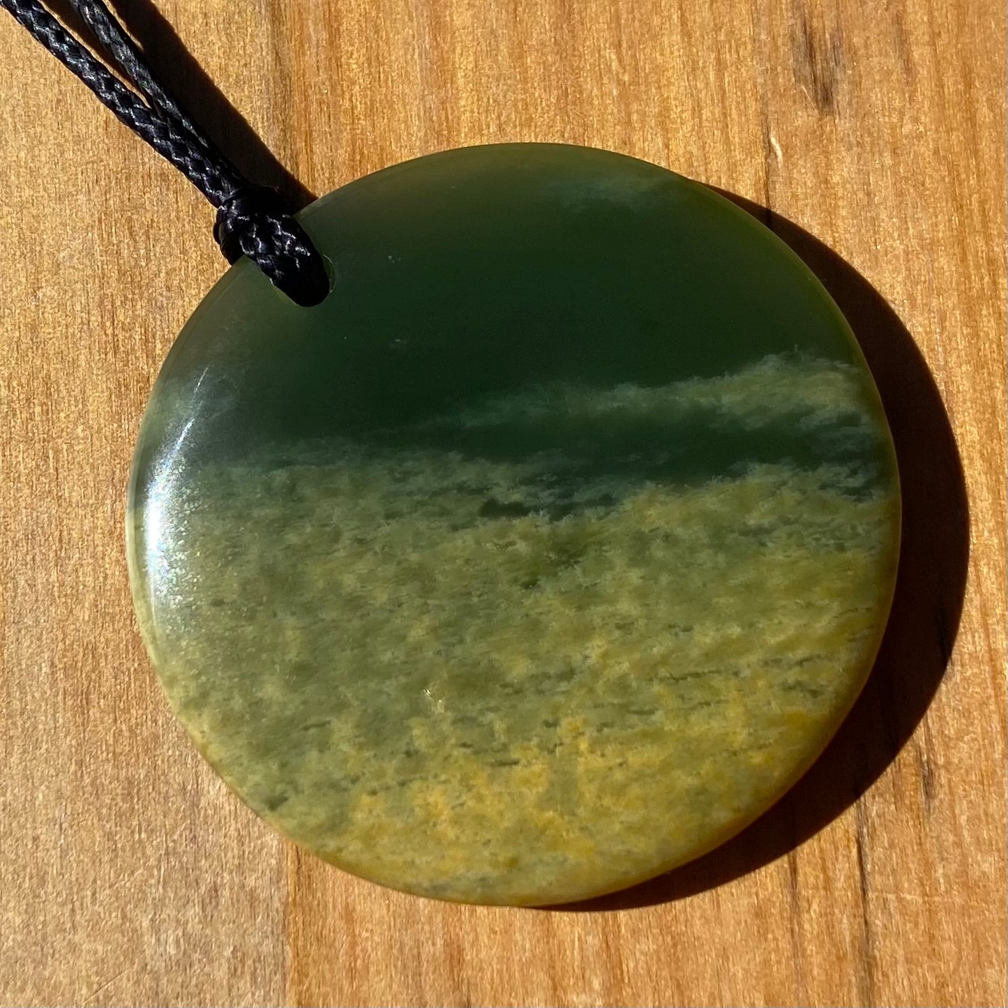 Pounamu porohita, disc, circle of life pendant from New Zealand Marsden Flower Jade pounamu (greenstone). Front.