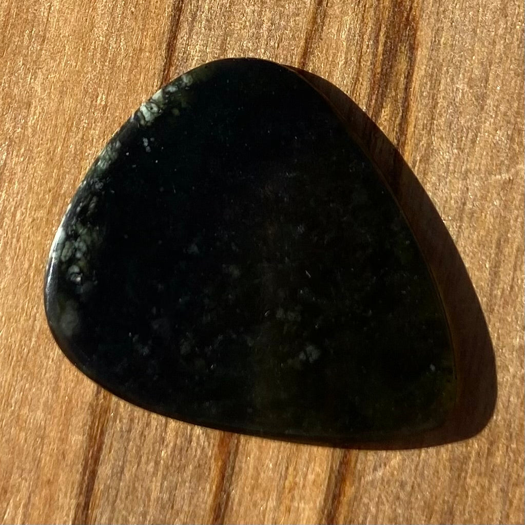 Guitar pick hand-carved from New Zealand tangiwai pounamu (greenstone). Front.