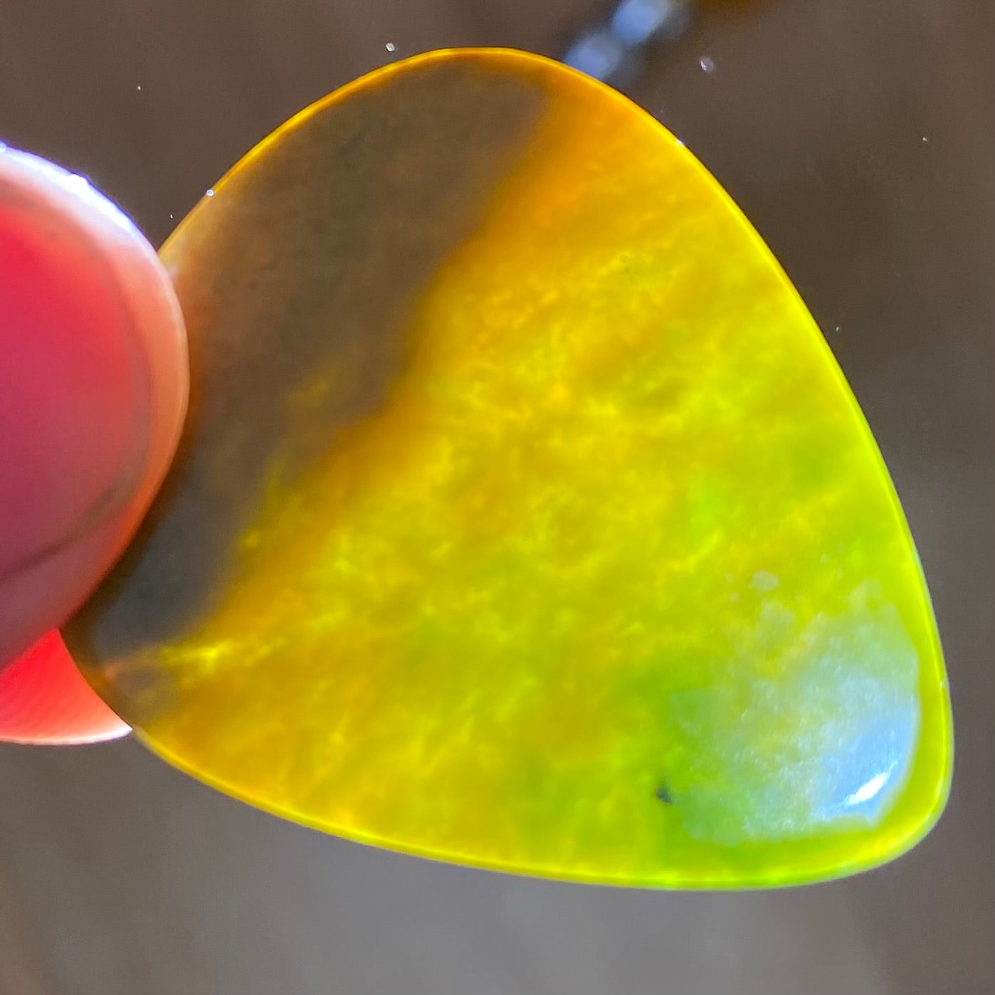 Pounamu guitar pick hand-carved from New Zealand Marsden flower jade pounamu (greenstone). Front.