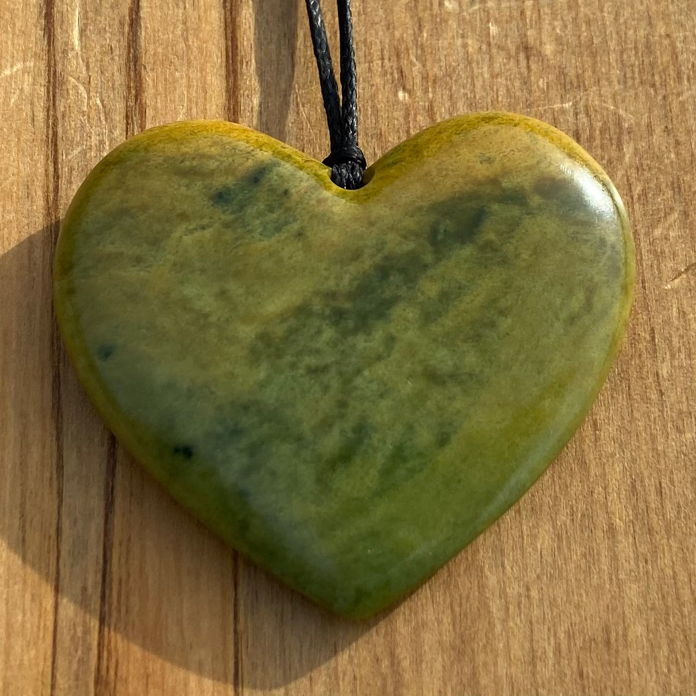Heart shape pendant carved from New Zealand Marsden Flower Jade (greenstone). Front.