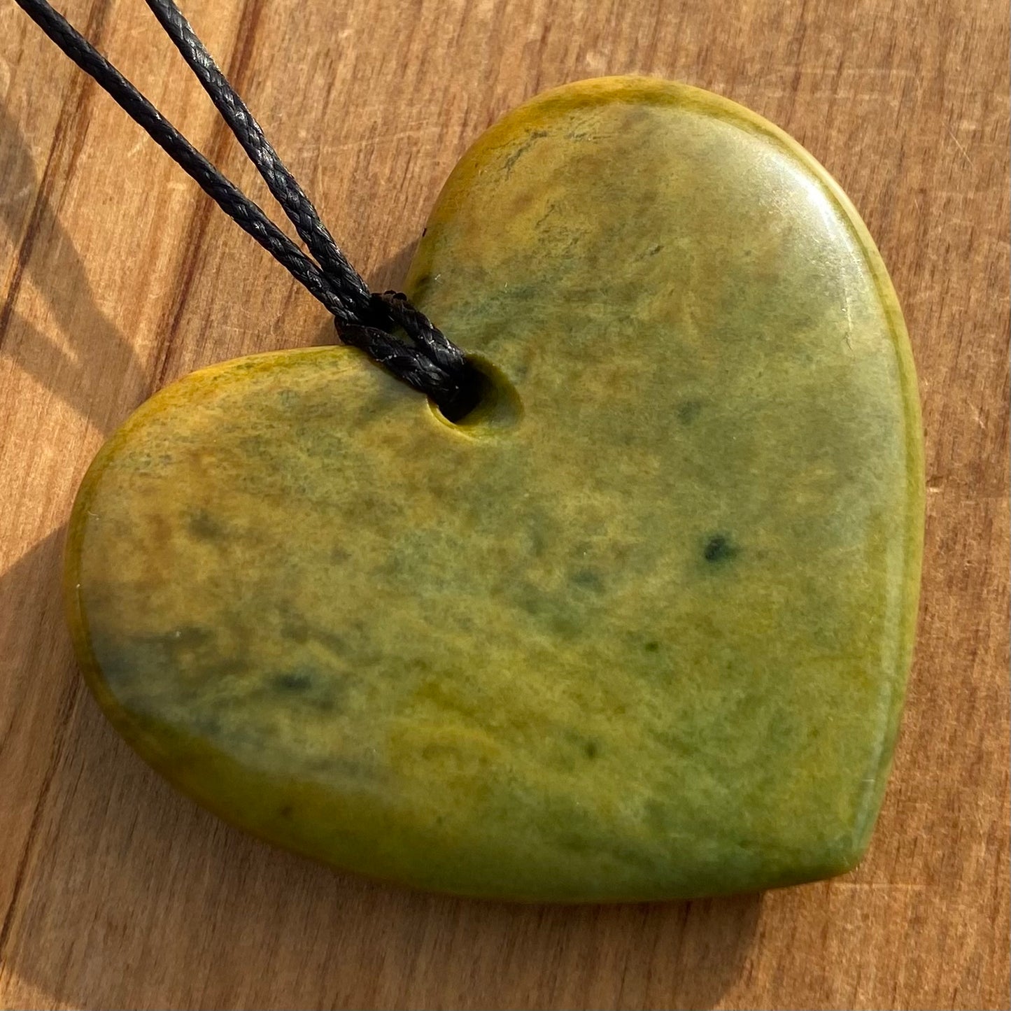 Heart shape pendant carved from New Zealand Marsden Flower Jade (greenstone). Back.
