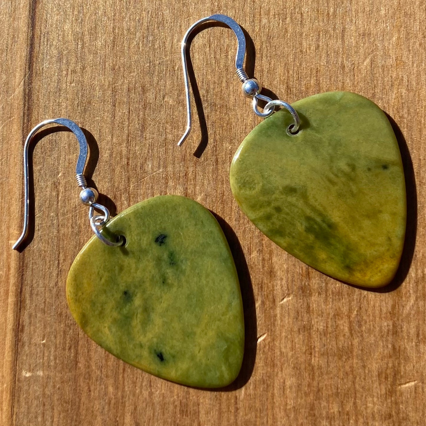 Guitar pick earrings hand-carved from New Zealand Marsden Flower Jade pounamu (greenstone) fitted with sterling silver. Front.