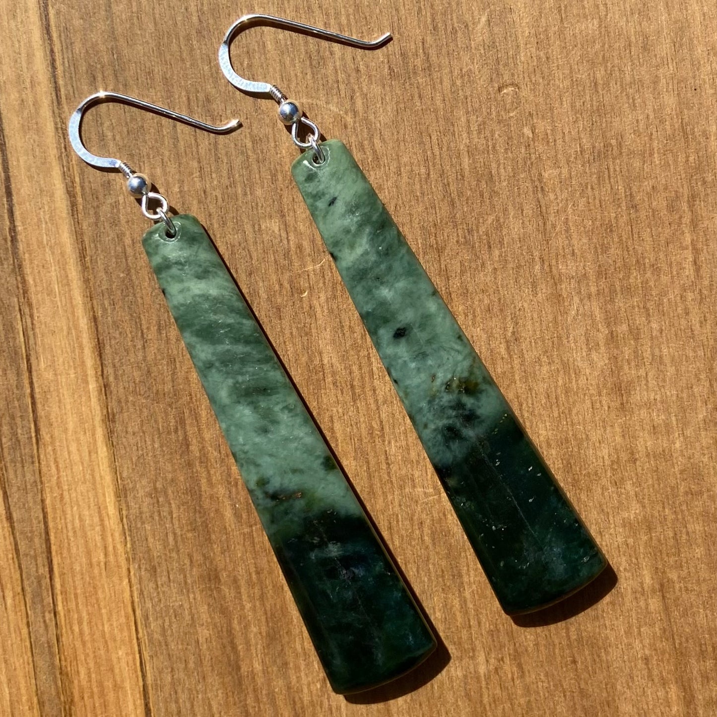 Pair of toki earrings hand-carved from New Zealand Kawakawa Jade/ pounamu (greenstone), with silver fittings. Front.