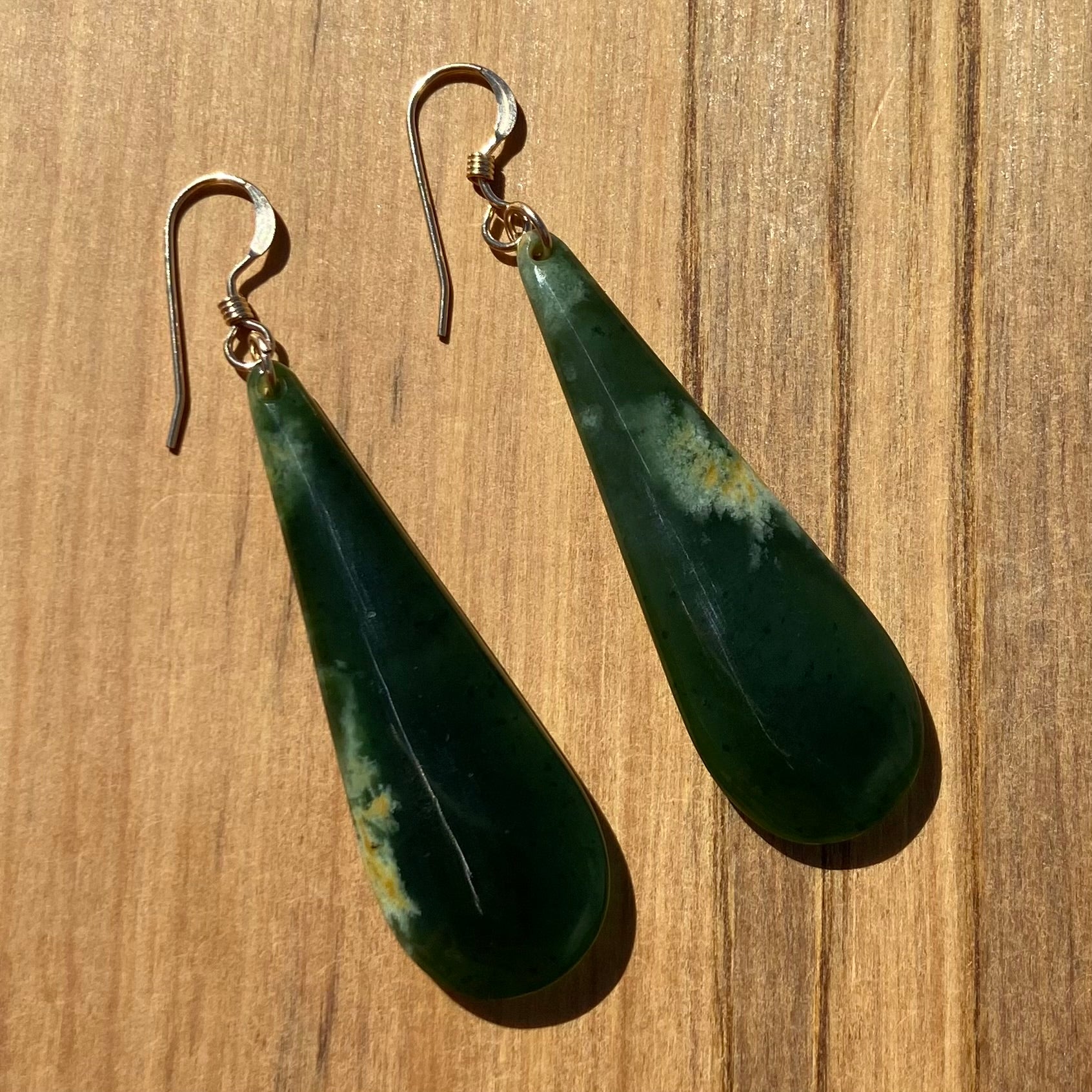 Pair of roimata (teardrop) earrings hand-carved from New Zealand Marsden Flower Jade/ pounamu (greenstone), with gold fittings. Back.