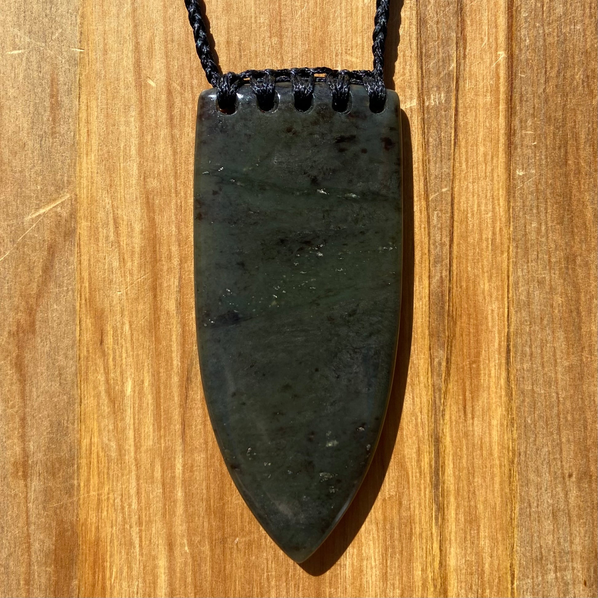 Bound Niho Tooth pendant hand-carved from New Zealand Kawakawa pounamu (greenstone). Front.