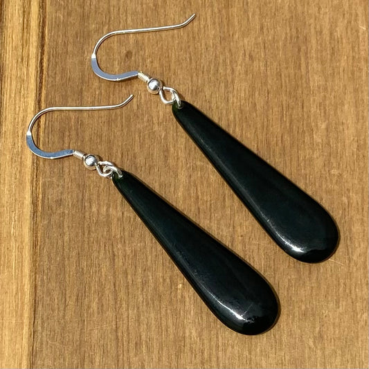 Pair of roimata earrings hand-carved from New Zealand Kawakawa Jade/ pounamu (greenstone), with silver fittings. Front.