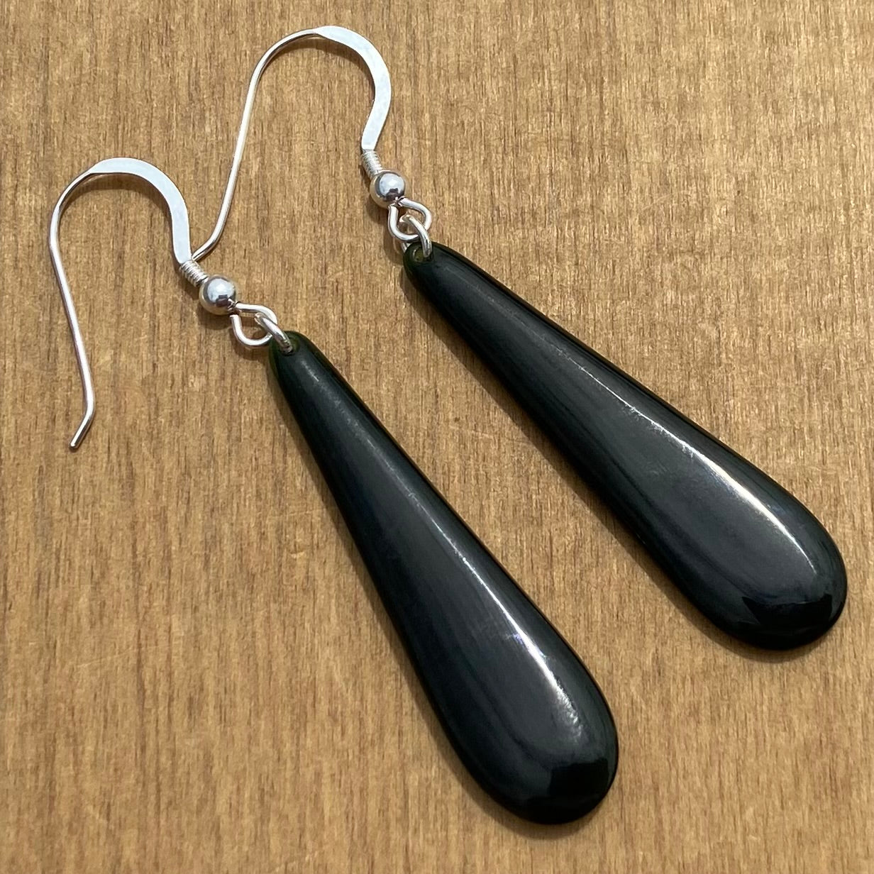 Pair of roimata earrings hand-carved from New Zealand Kawakawa Jade/ pounamu (greenstone), with silver fittings. Back,