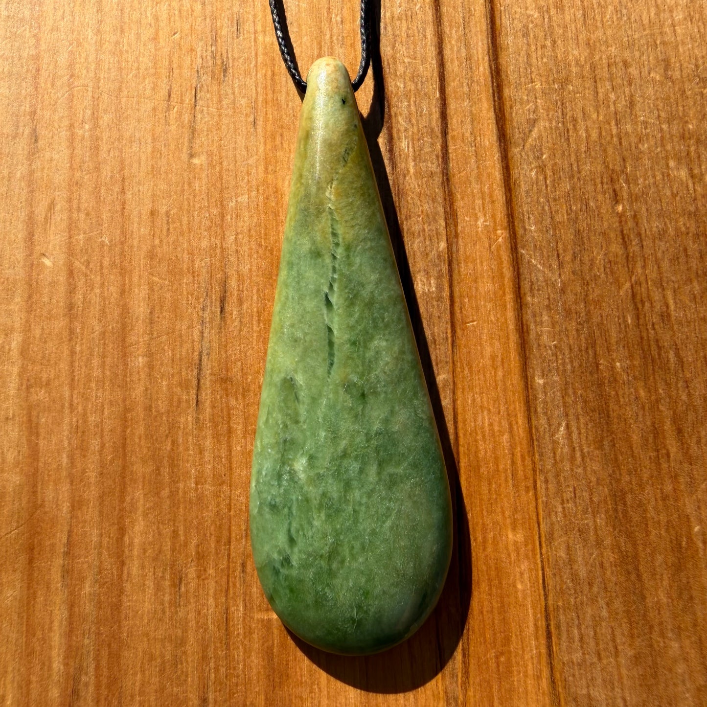 Roimata (teardrop) pendant hand-carved from New Zealand Marsden Flower Jade/ pounamu (greenstone). Front.
