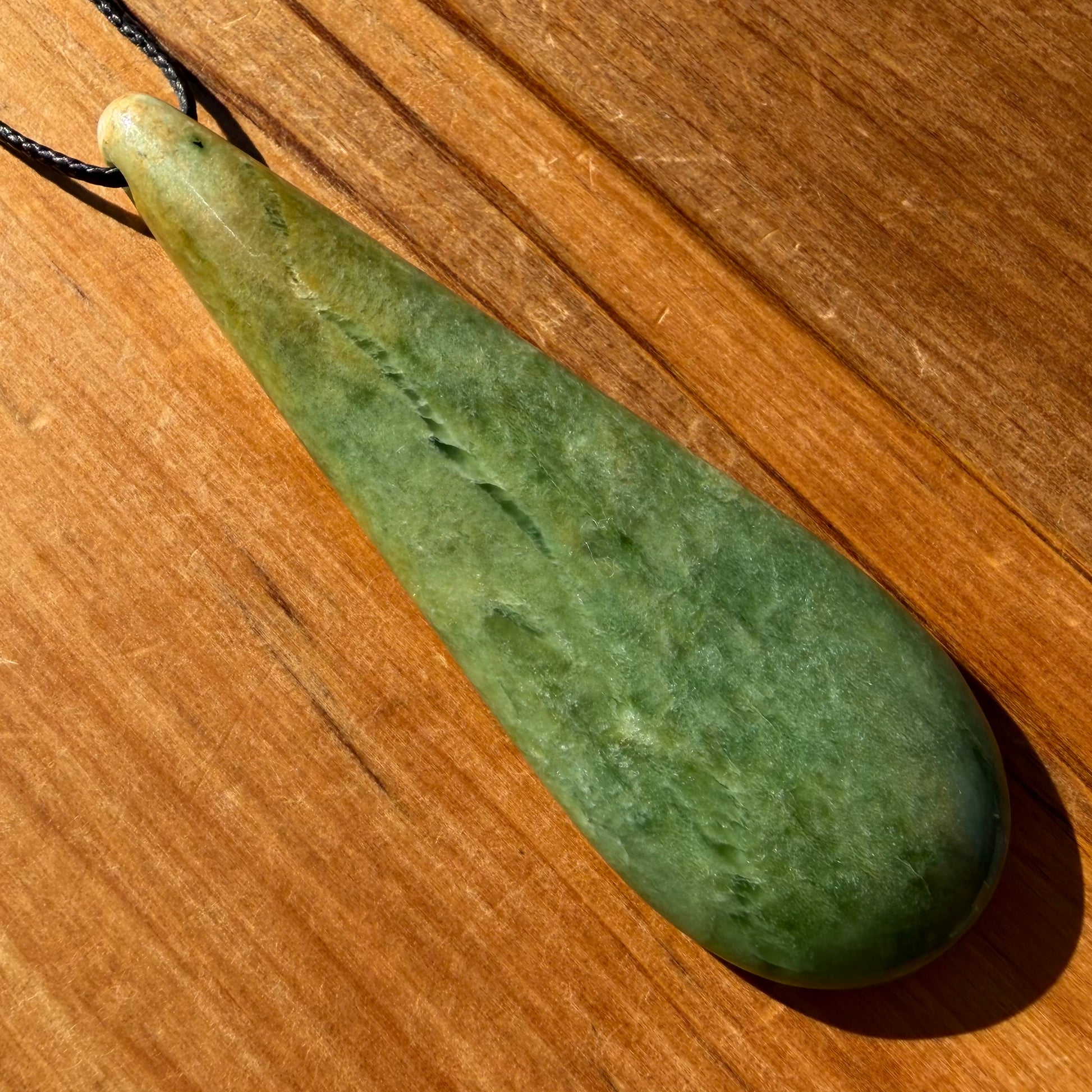 Roimata (teardrop) pendant hand-carved from New Zealand Marsden Flower Jade/ pounamu (greenstone). Front.
