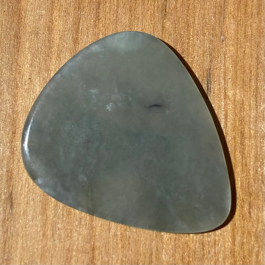 Guitar pick hand-carved from New Zealand Inanga Greenstone pounamu (greenstone). Front.