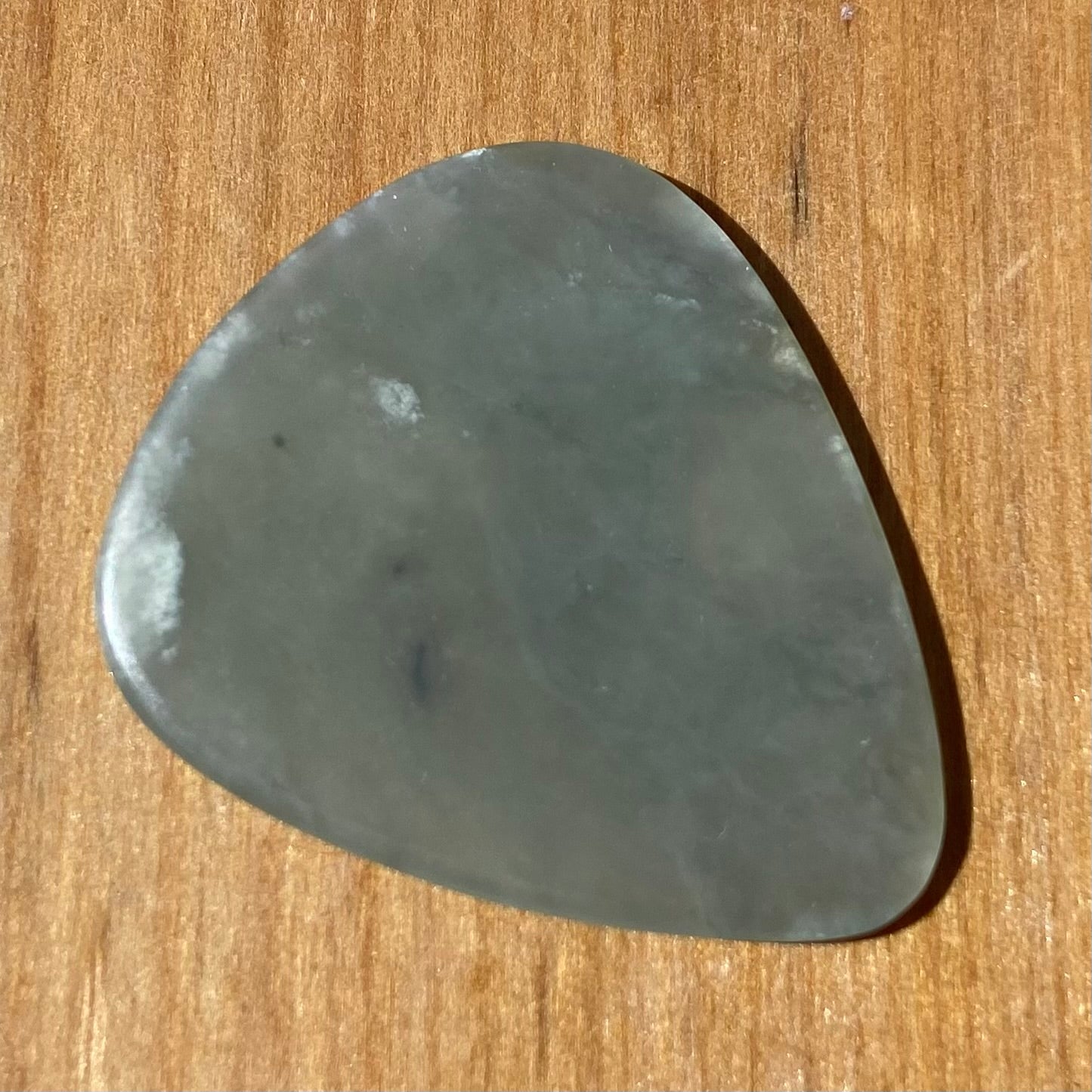Guitar pick hand-carved from New Zealand Inanga Greenstone pounamu (greenstone). Back.
