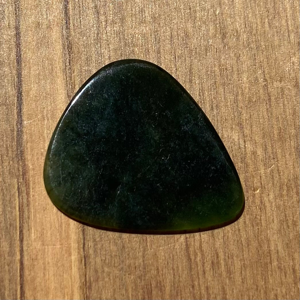 Guitar pick hand-carved from New Zealand Kawakawa Greenstone pounamu (greenstone). Front.