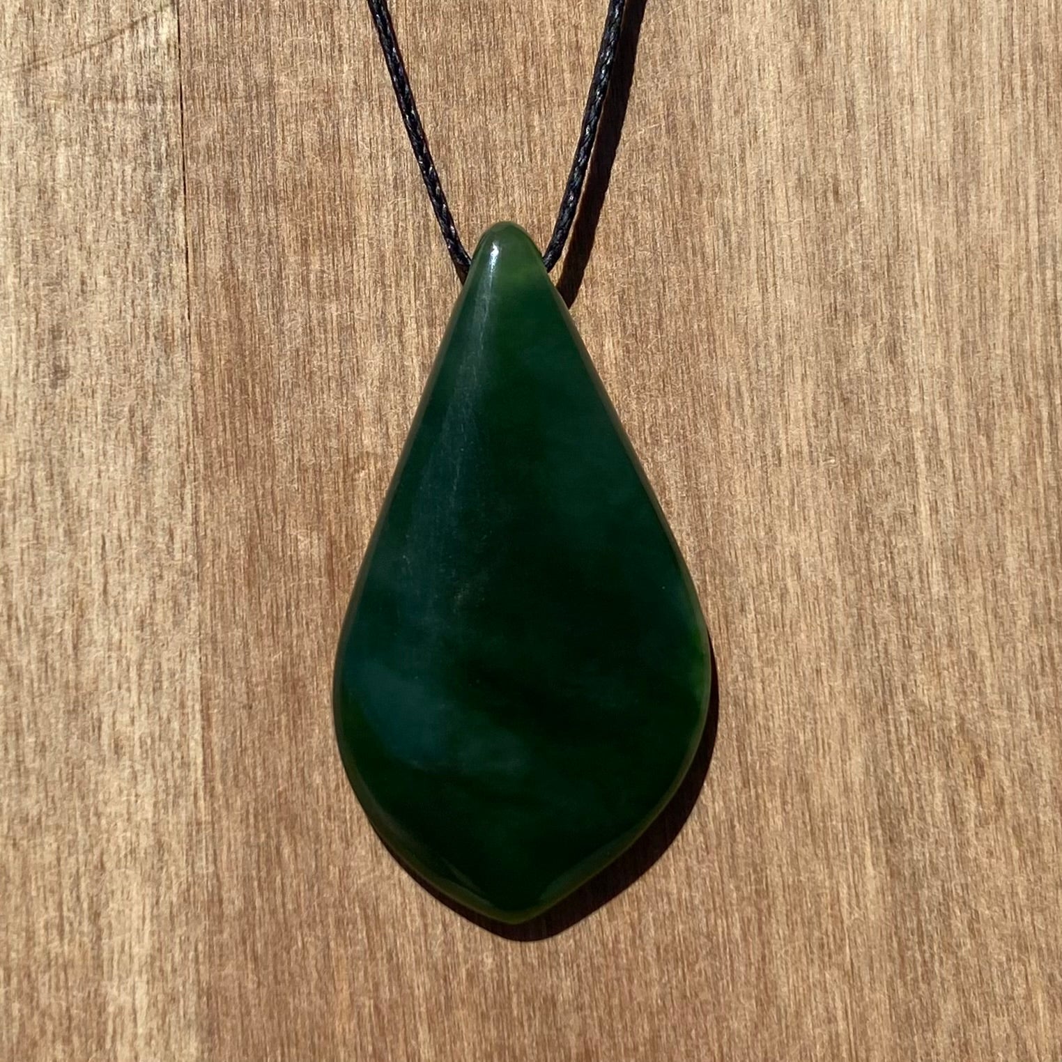 Freeform shape pendant hand-carved from New Zealand kahurangi  pounamu (greenstone). Front.