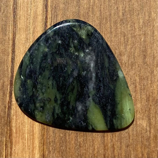 Guitar pick hand-carved from New Zealand Douglas Creek pounamu (greenstone). Front.