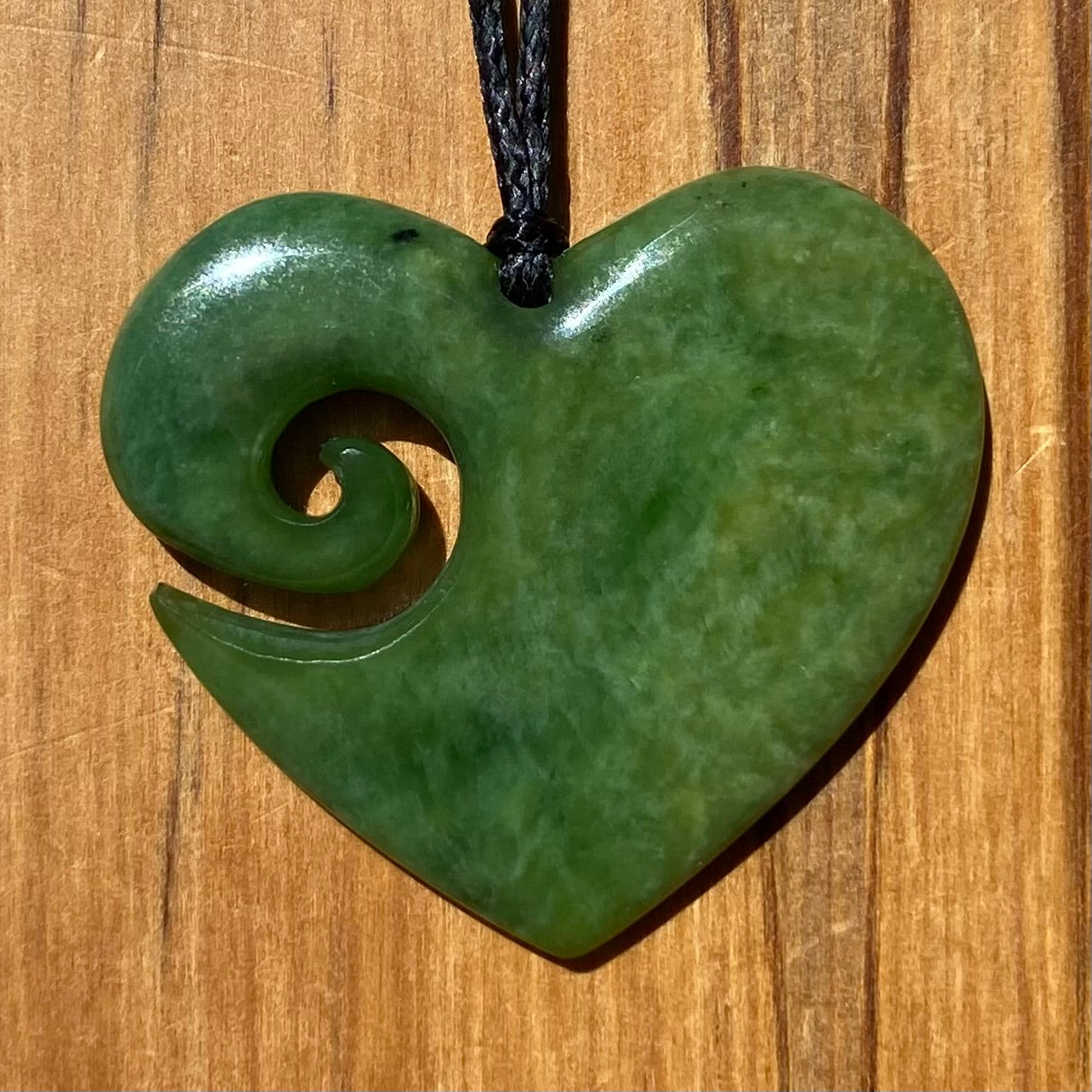 Koru heart shape pendant carved from New Zealand Marsden Flower Jade (greenstone). Front.