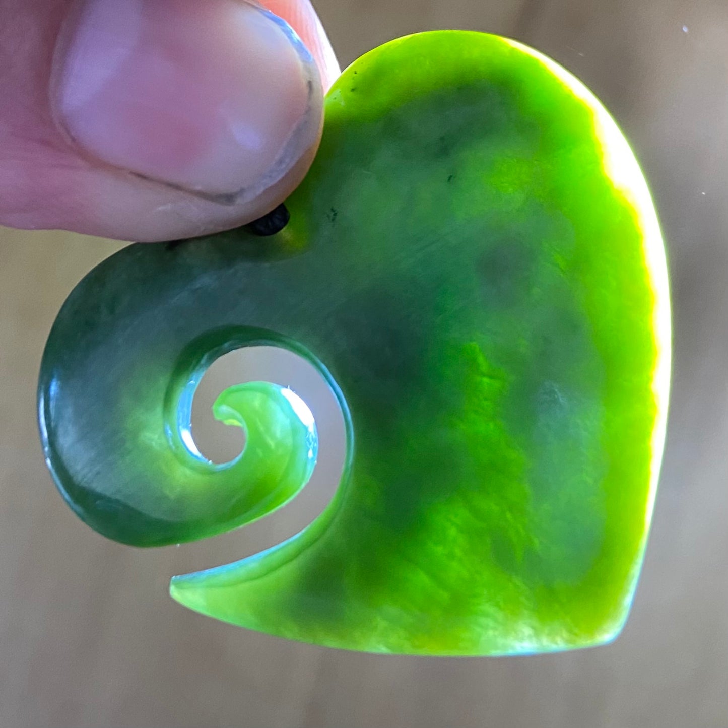 Koru heart shape pendant carved from New Zealand Marsden Flower Jade (greenstone). Translucency.