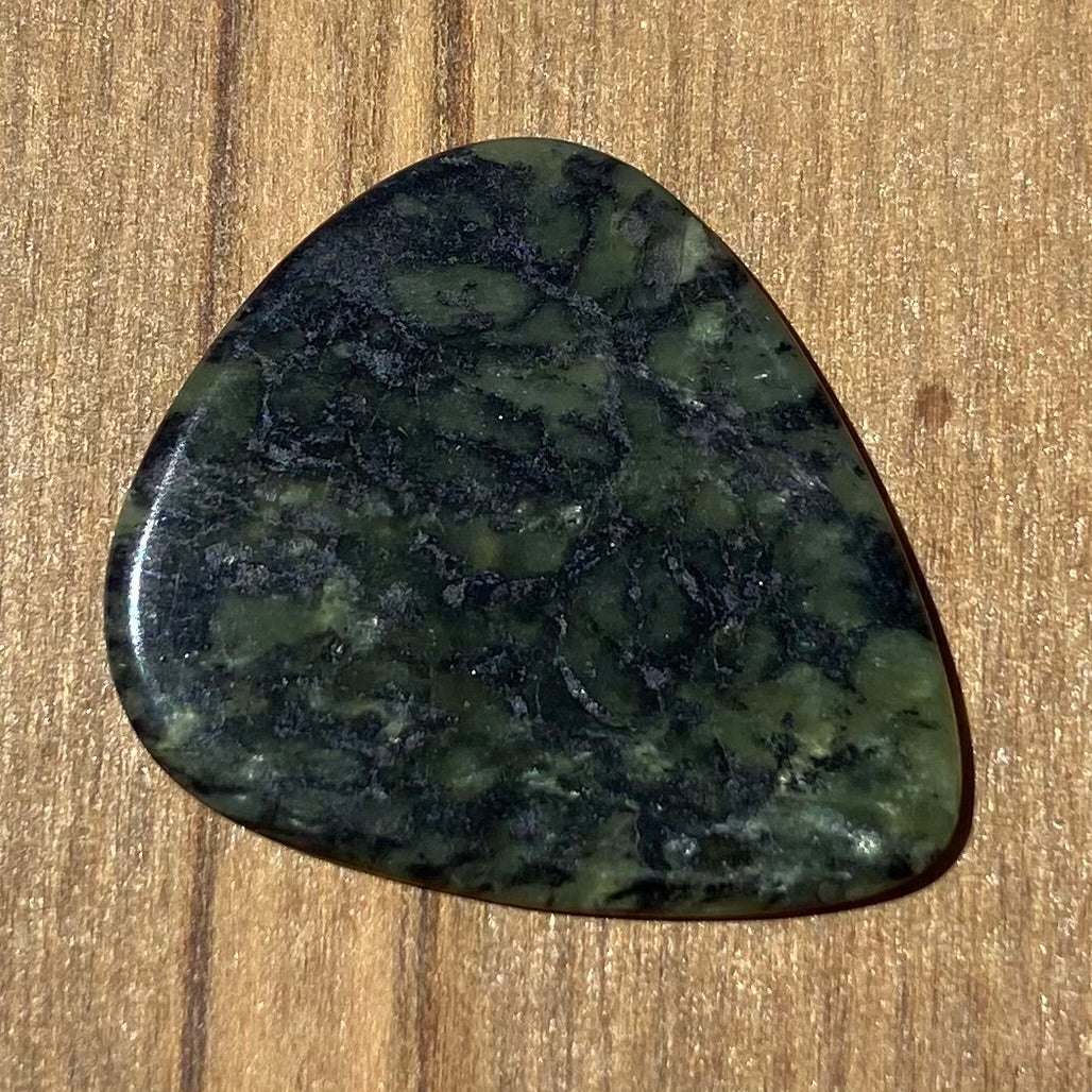 Guitar pick hand-carved from New Zealand Douglas Creek pounamu (greenstone). Front.