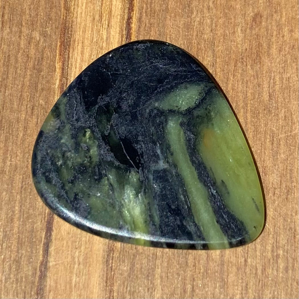 Guitar pick hand-carved from New Zealand Douglas Creek pounamu (greenstone). Back.