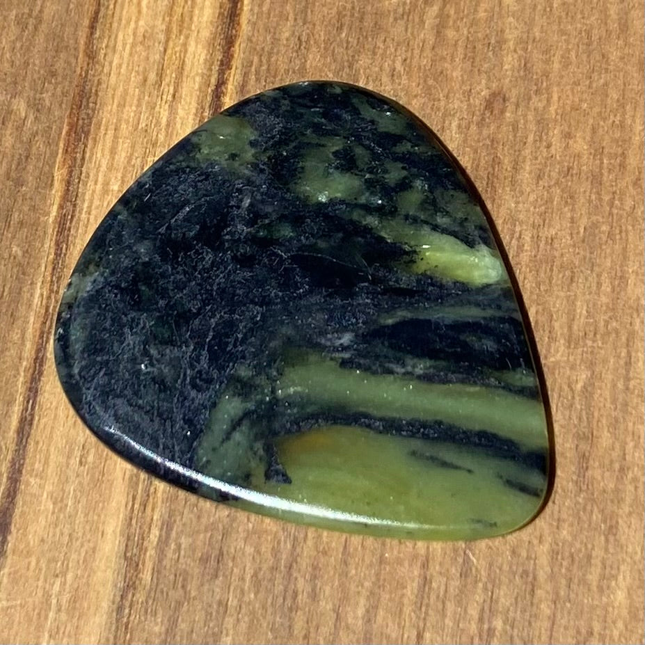 Guitar pick hand-carved from New Zealand Douglas Creek pounamu (greenstone). Front.