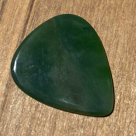 Guitar pick hand-carved from New Zealand Kahurangi Greenstone pounamu (greenstone). Front.