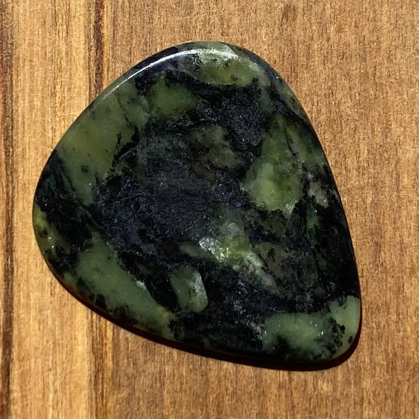 Guitar pick hand-carved from New Zealand Douglas Creek pounamu (greenstone). Front.