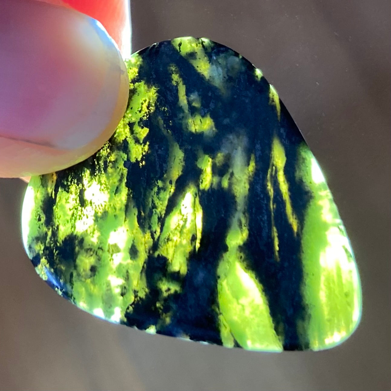 Guitar pick hand-carved from New Zealand Douglas Creek pounamu (greenstone). Translucency. 