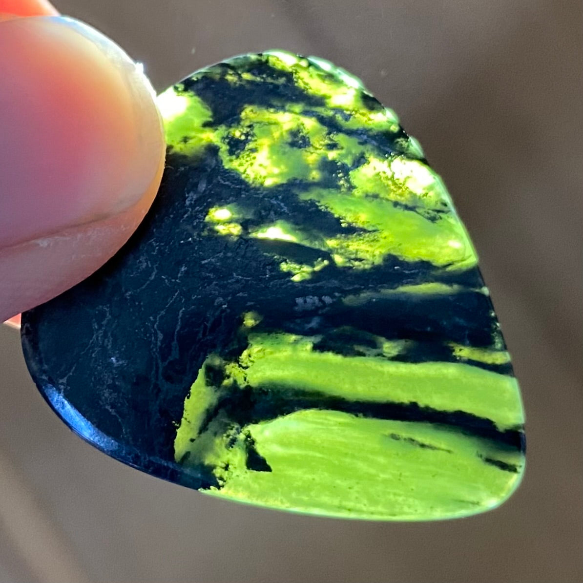 Guitar pick hand-carved from New Zealand Douglas Creek pounamu (greenstone). Translucency.