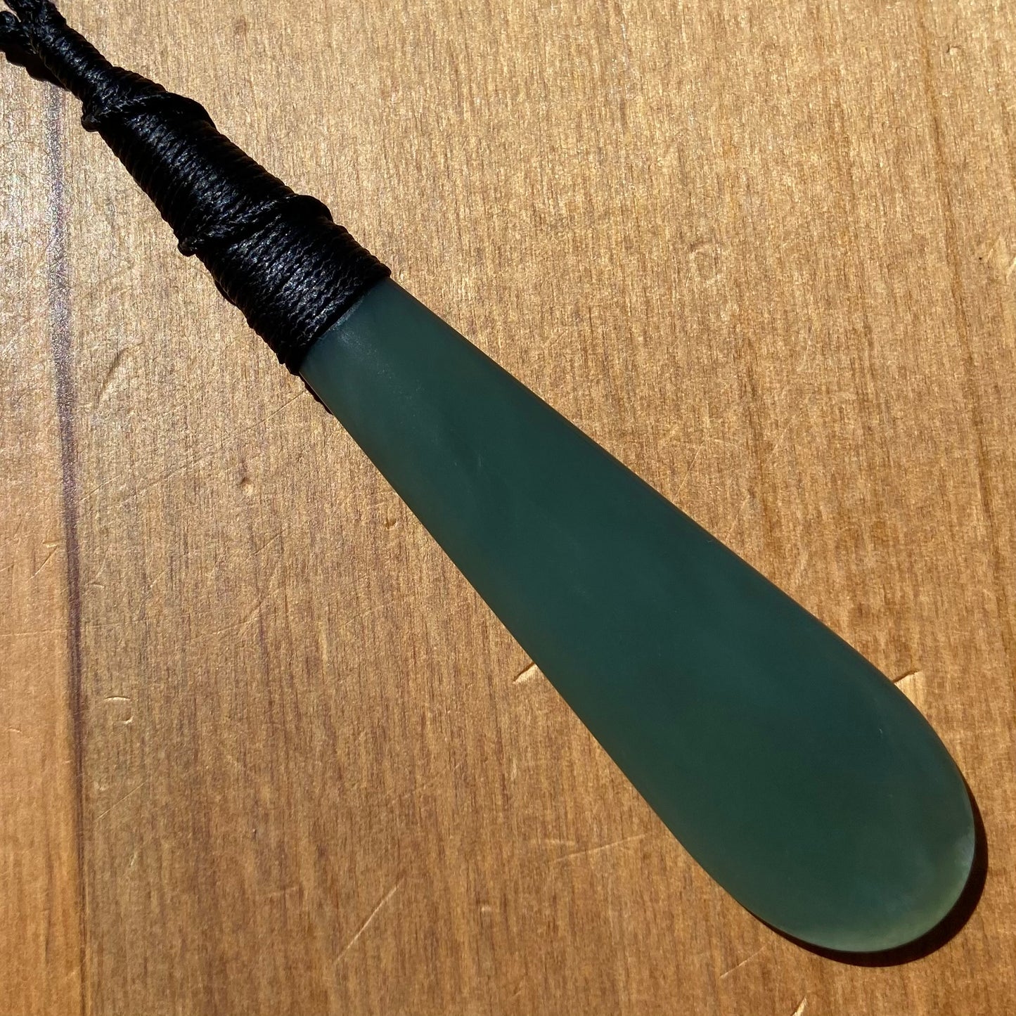 Bound roimata teardrop pendant carved from New Zealand inanga pounamu (greenstone). Front.