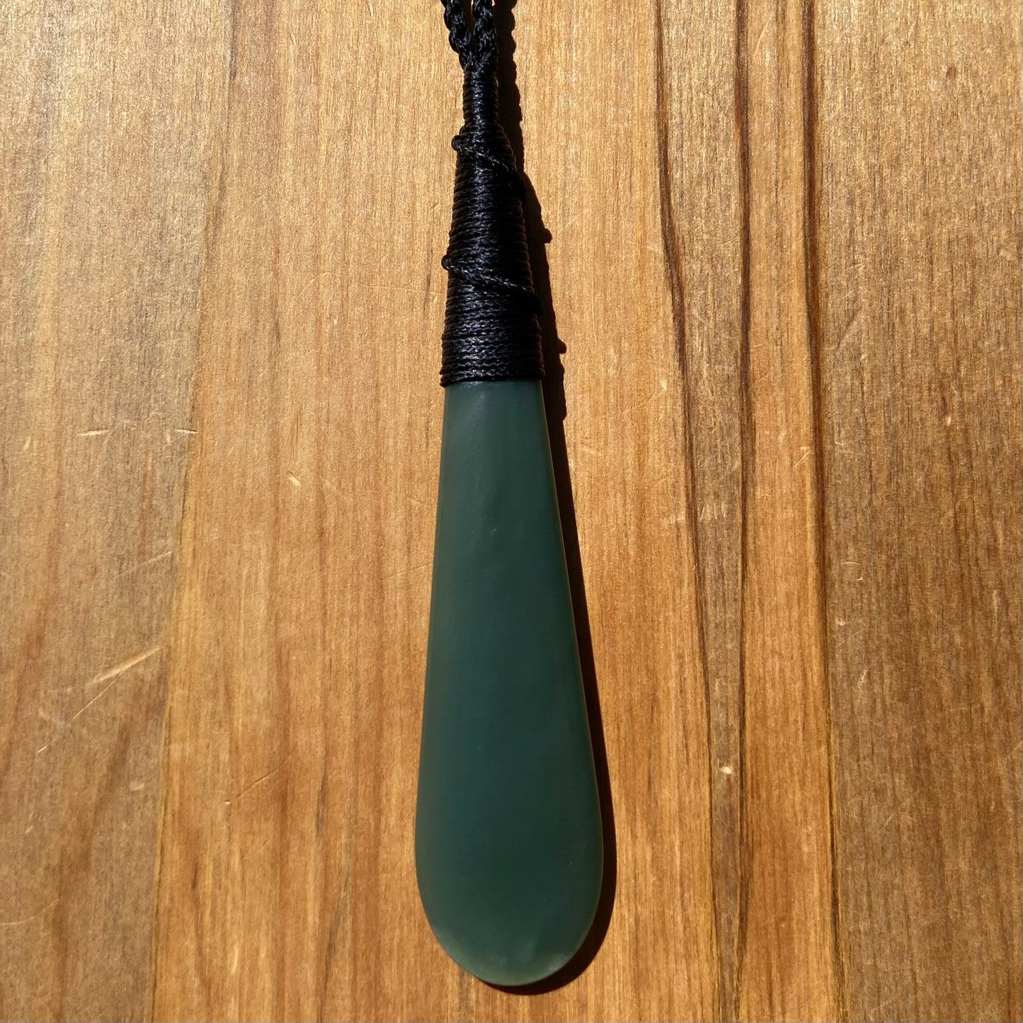 Bound roimata teardrop pendant carved from New Zealand inanga pounamu (greenstone). Front.