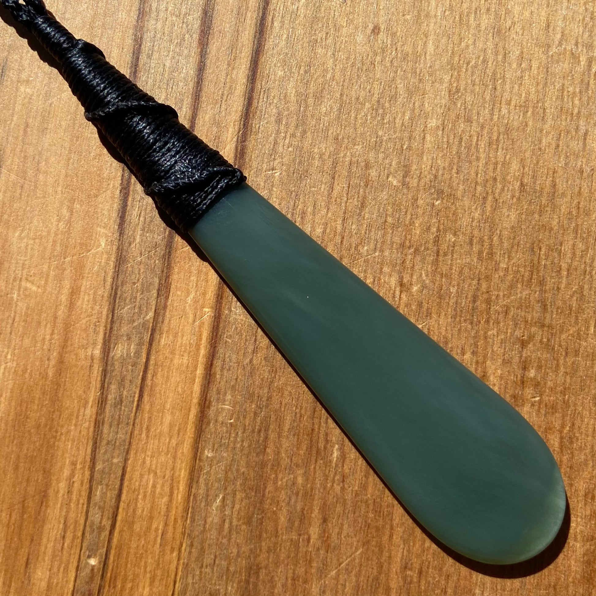 Bound roimata teardrop pendant carved from New Zealand inanga pounamu (greenstone). Back.