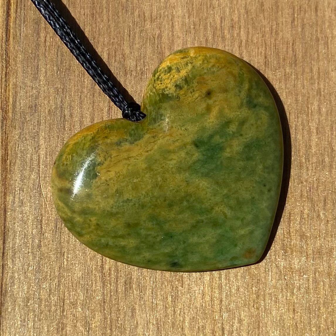 Heart shape pendant carved from New Zealand Marsden Flower Jade (greenstone). Angle.