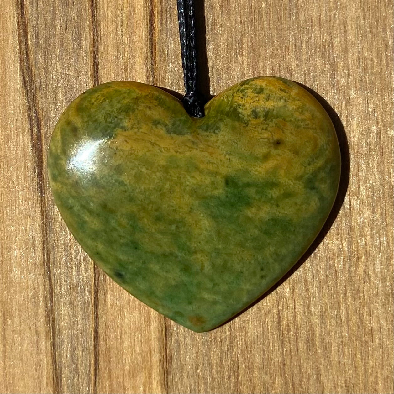 Heart shape pendant carved from New Zealand Marsden Flower Jade (greenstone). Front.