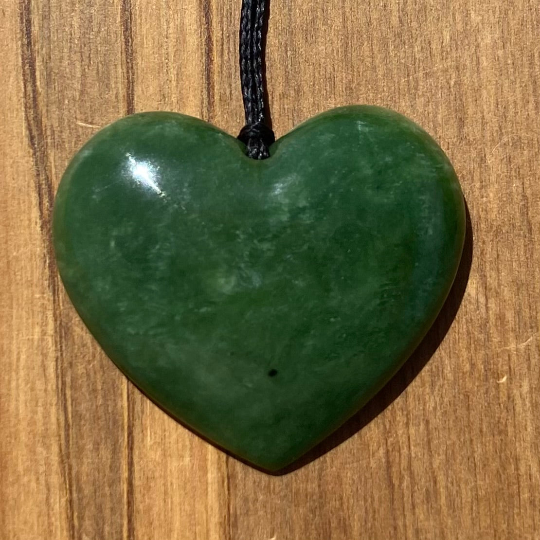 Heart shape pendant carved from New Zealand Marsden Flower Jade (greenstone). Angle.