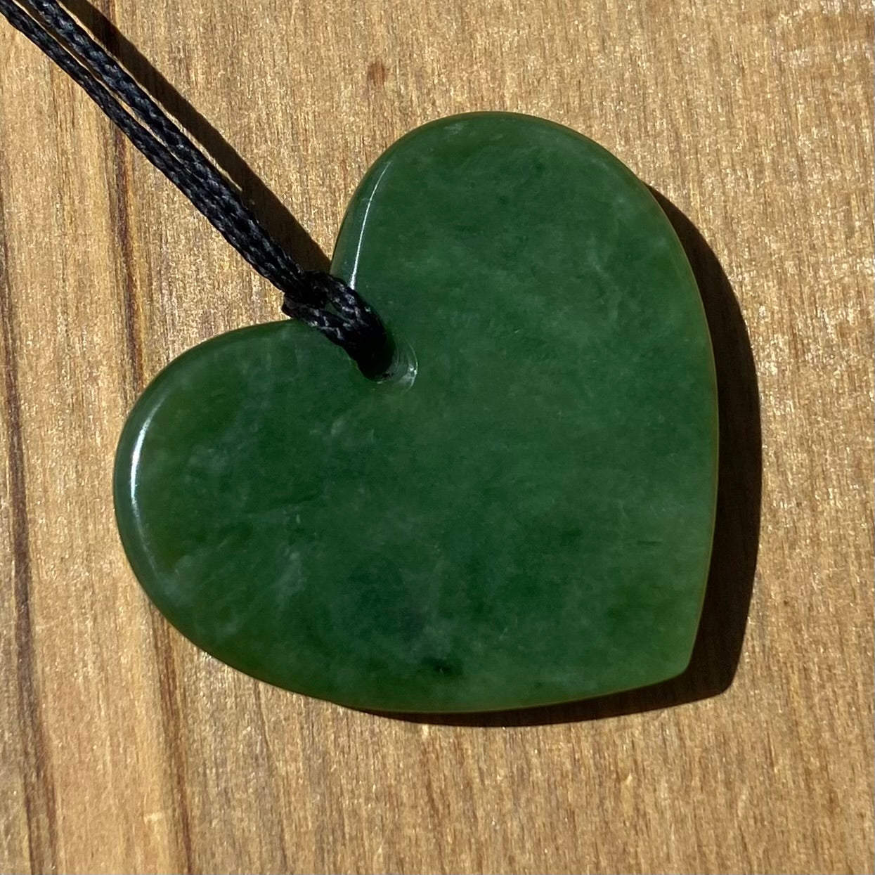 Heart shape pendant carved from New Zealand Marsden Flower Jade (greenstone). Back.