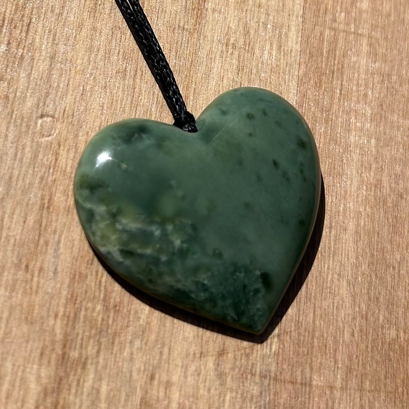 Heart shaped pendant hand-carved from New Zealand inanga pounamu (greenstone). Front.