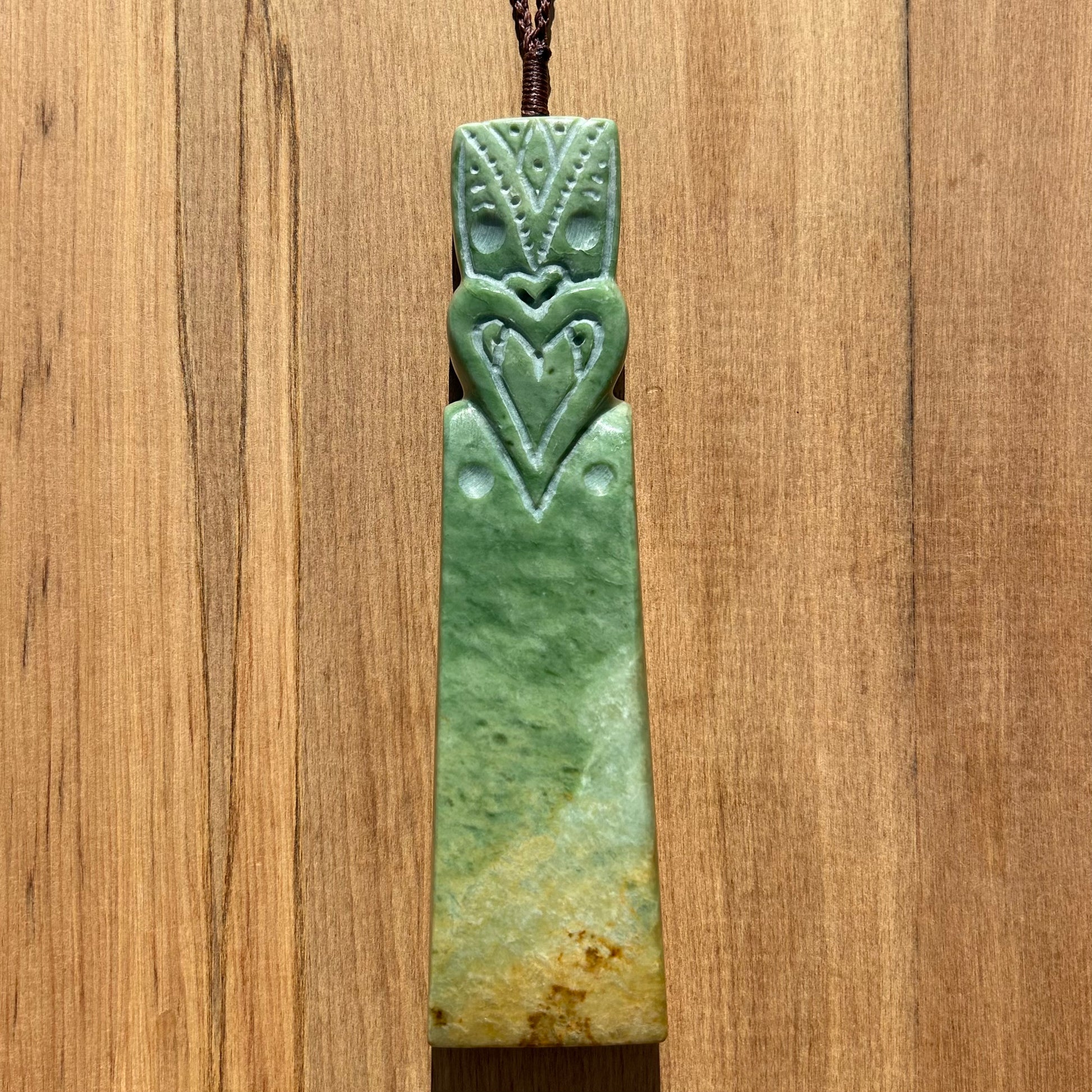 Tekoteko toki pendant hand-carved from New Zealand Marsden Flower Jade/ pounamu (greenstone). Front vertical.