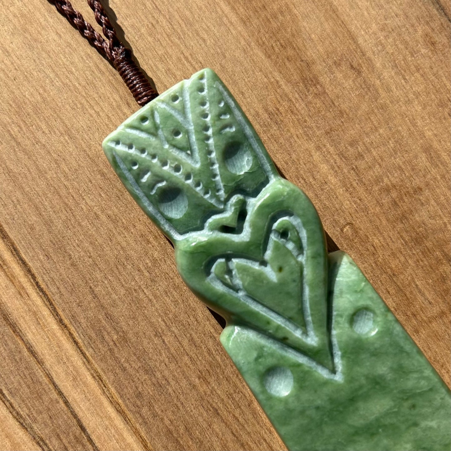 Tekoteko toki pendant hand-carved from New Zealand Marsden Flower Jade/ pounamu (greenstone). Close up of face..