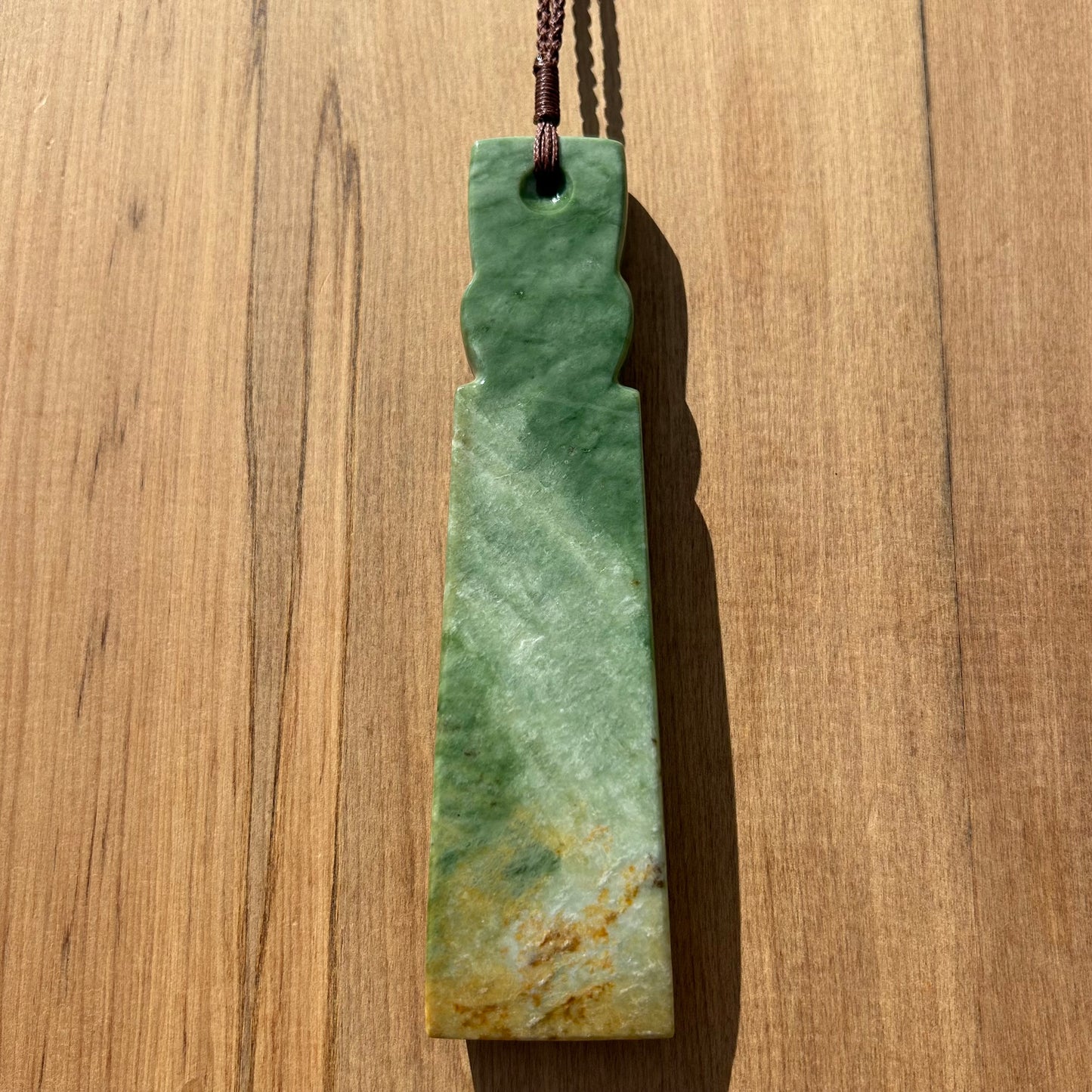 Tekoteko toki pendant hand-carved from New Zealand Marsden Flower Jade/ pounamu (greenstone). Back.