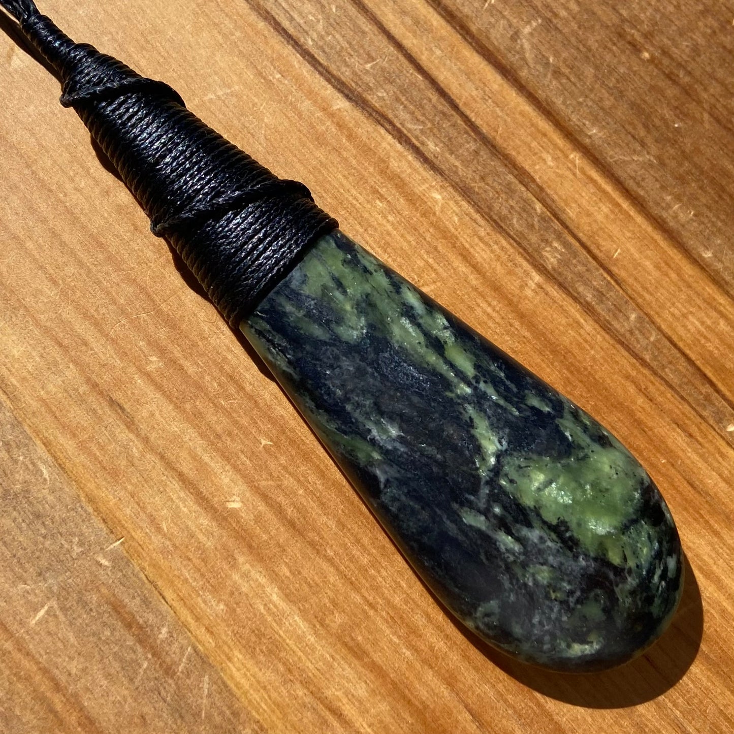 Bound roimata (teardrop) pendant hand-carved from New Zealand Douglas Creek pounamu (greenstone). Front.