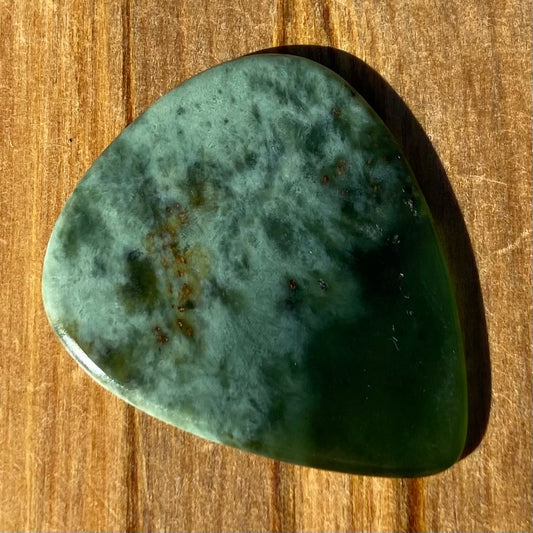 Guitar pick hand-carved from New Zealand Kawakawa Greenstone pounamu (greenstone). Front.