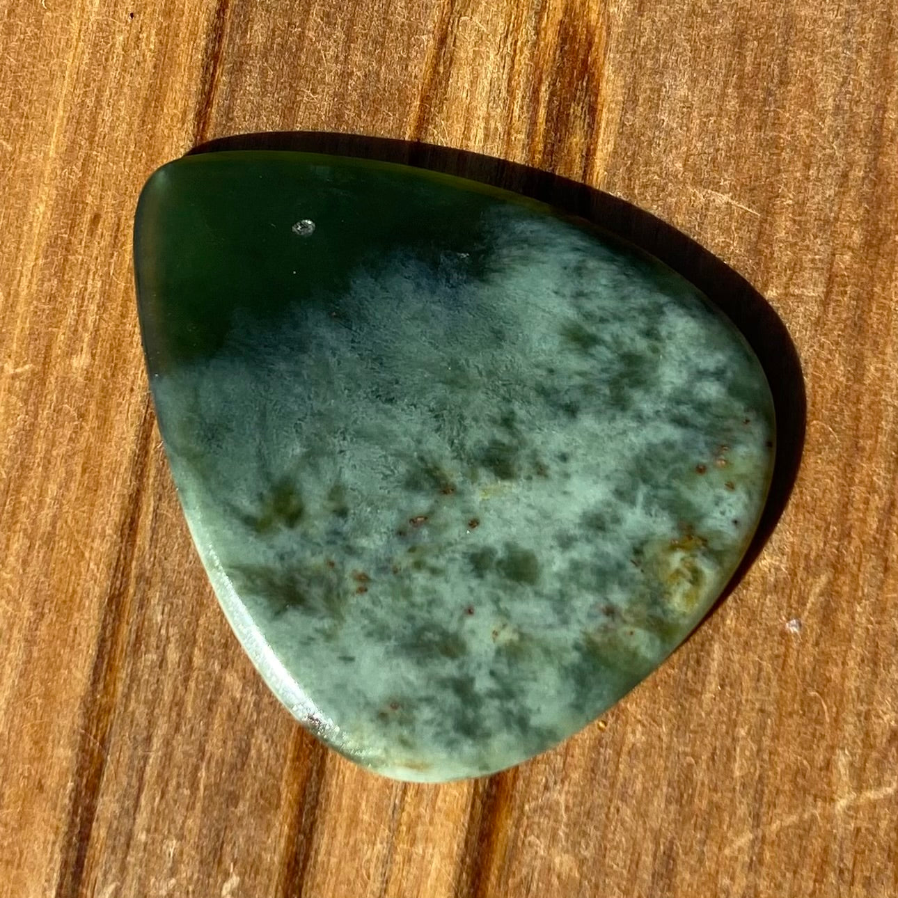 Guitar pick hand-carved from New Zealand Kawakawa Greenstone pounamu (greenstone). Front.