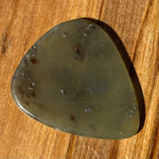 Guitar pick hand-carved from New Zealand Kawakawa Greenstone pounamu (greenstone). Front.