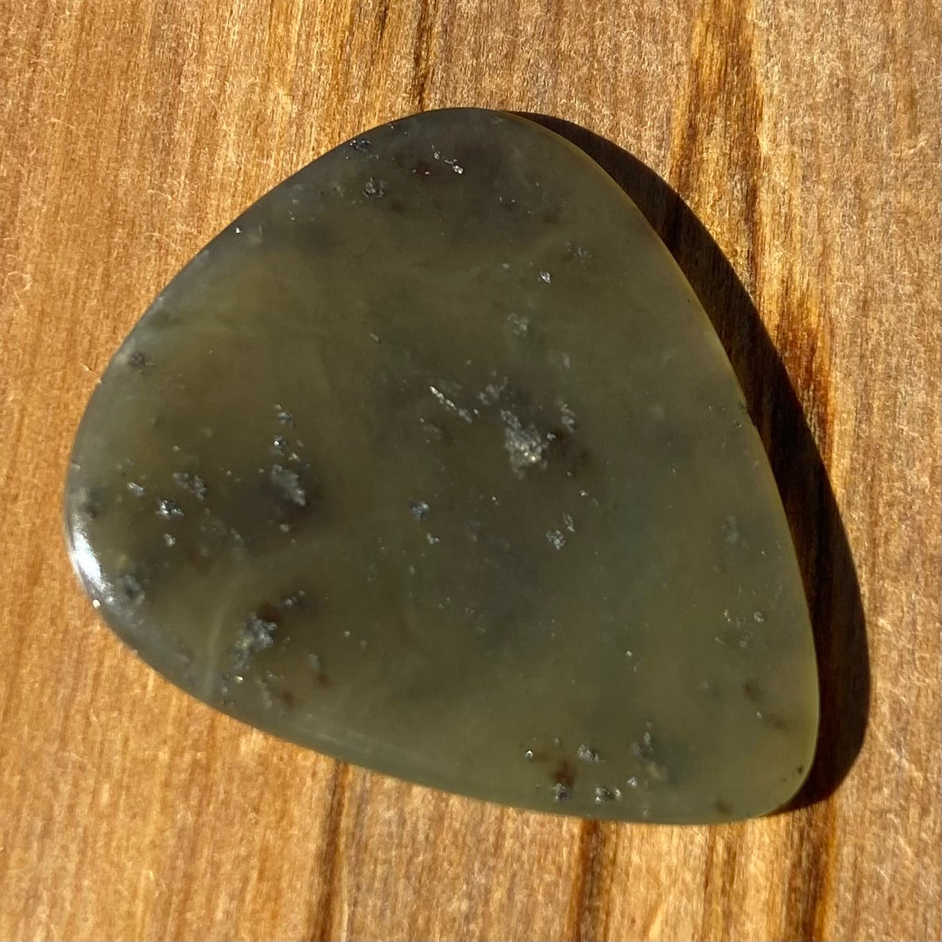 Guitar pick hand-carved from New Zealand Kawakawa Greenstone pounamu (greenstone). Front.