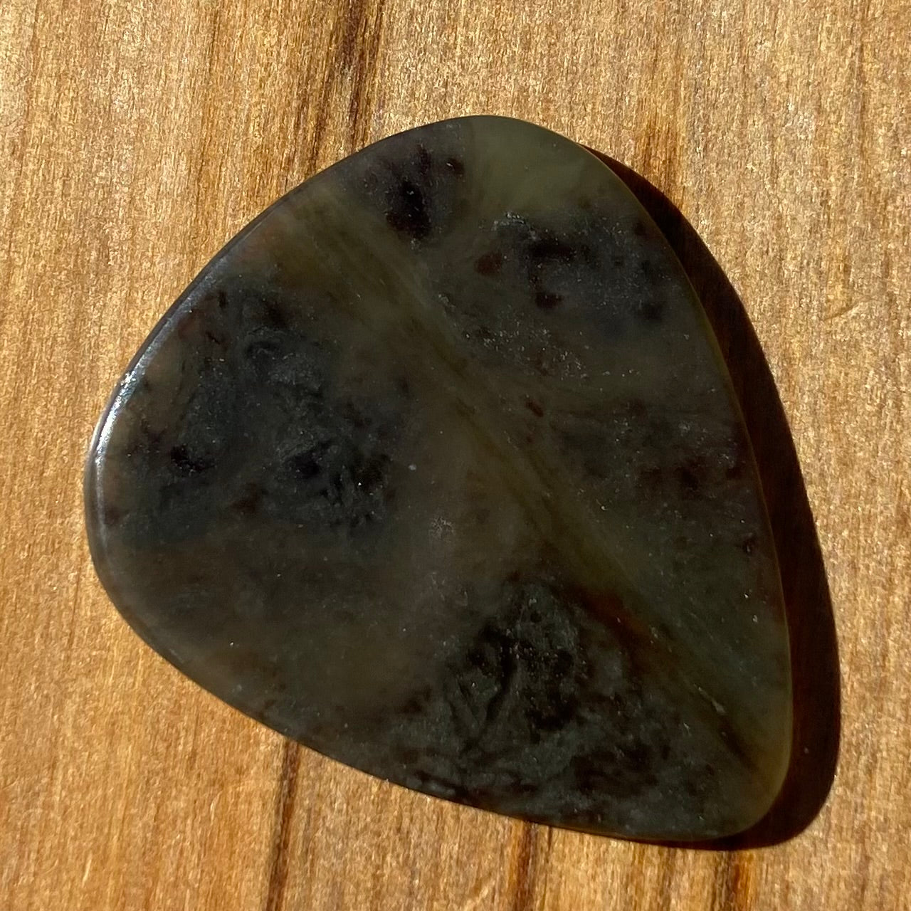 Guitar pick hand-carved from New Zealand Kawakawa Greenstone pounamu (greenstone). Front.