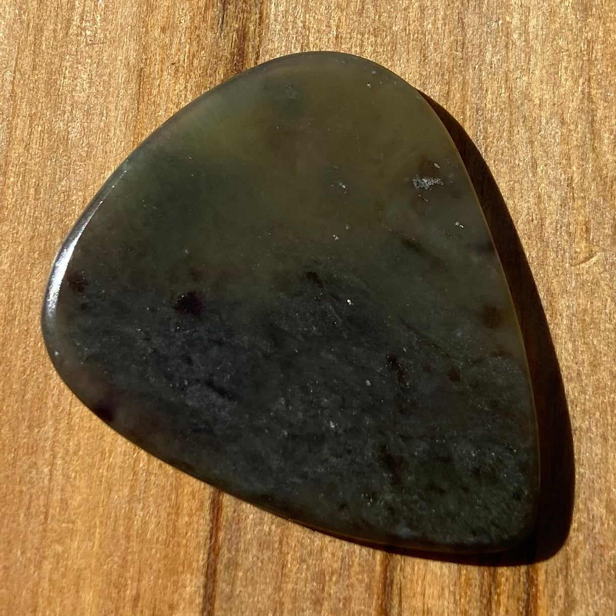 Guitar pick hand-carved from New Zealand Kawakawa Greenstone pounamu (greenstone). Front.