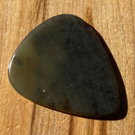 Guitar pick hand-carved from New Zealand Kawakawa Greenstone pounamu (greenstone). Front.